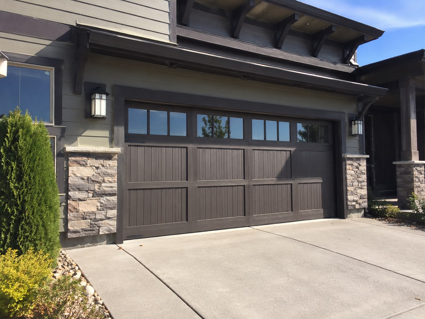Newer La Habra Craftsman home with a dark wood-look carriage garage door and stone columns